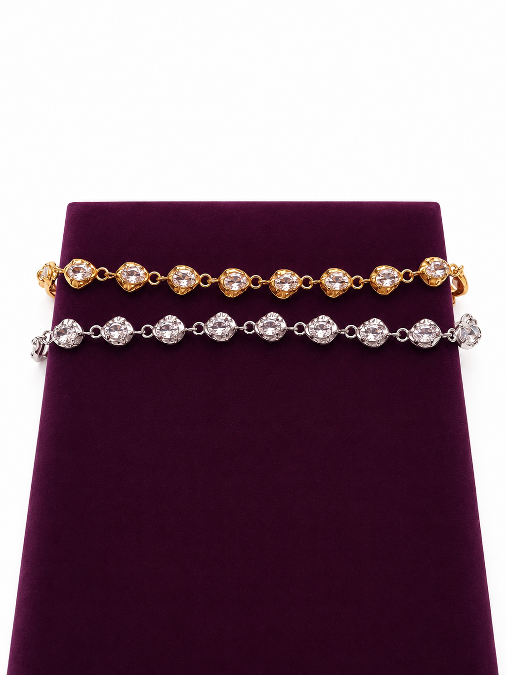 Two zircon bracelets displayed on a dark purple velvet jewelry stand against a white background. The top bracelet is 18K gold-plated with oval-cut zircons, and the bottom bracelet is silver-toned with oval-cut zircons.