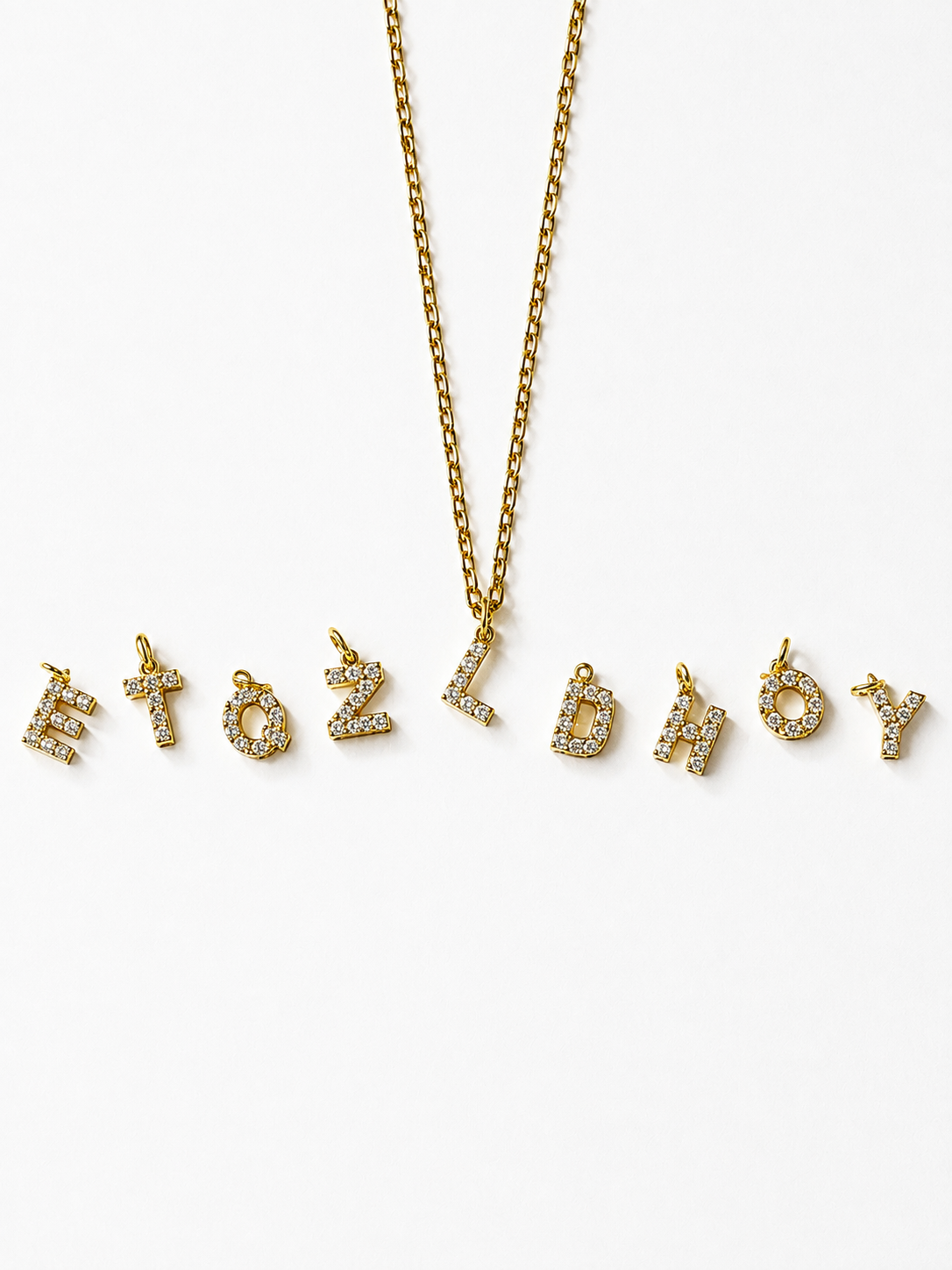 A 18K gold-plated gold chain necklace with gold initial pendants paved with small clear rhinestones